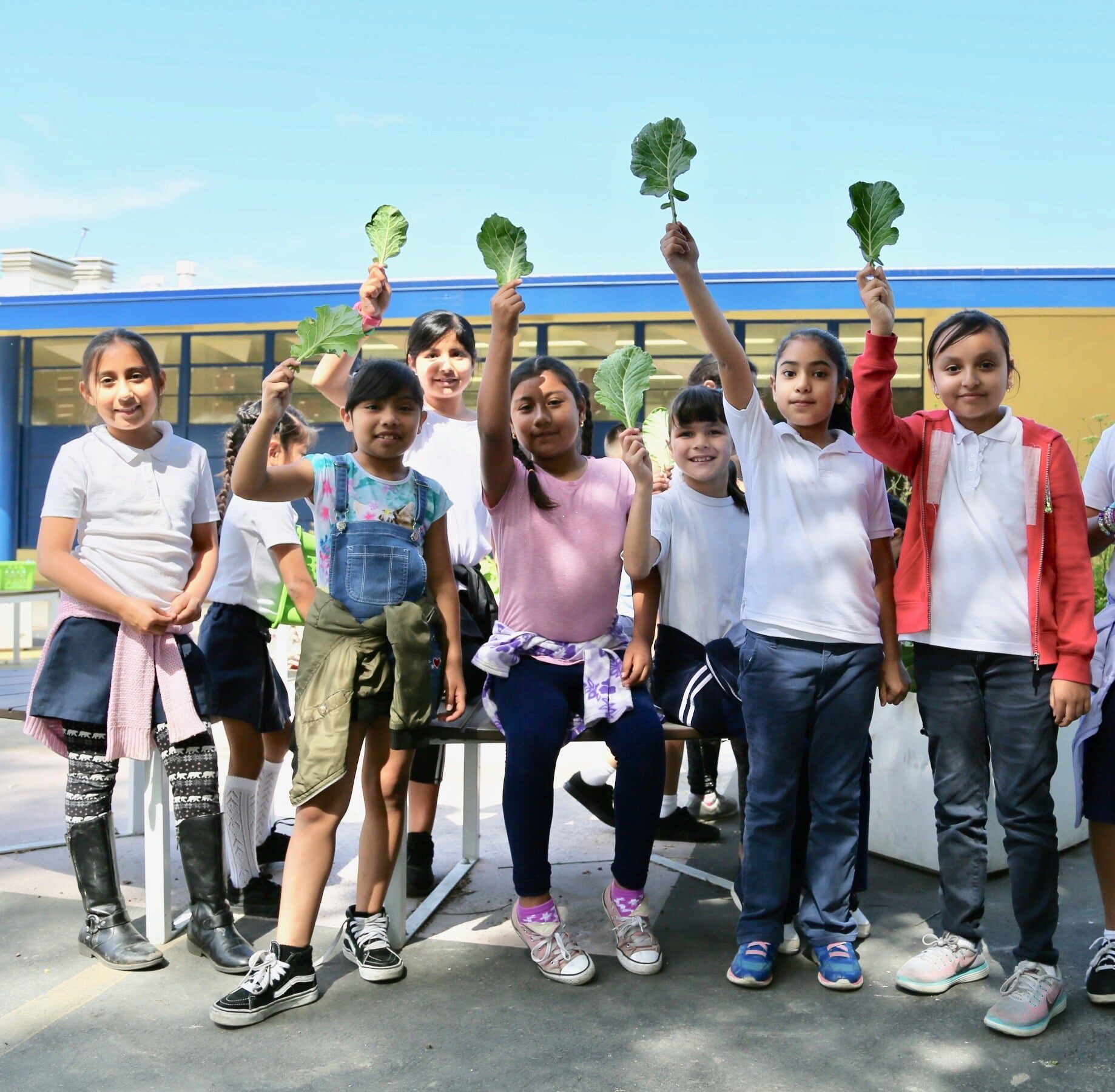 a group of students holding up vegetables.