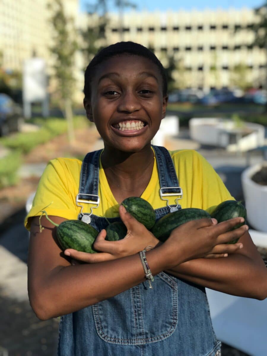 Girl smiling and holding squash with overalls
